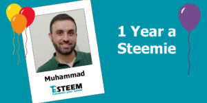 image shows a teal background with a polaroid image on the left with a pciture of Muhammad his name and the Esteem logo. There are also red yellow and orange balloons to the left. To the right of the image there are words in white "1 year a Steemie" with a purple balloon next to it